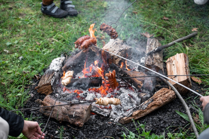špekáčky na prutech se opékají nad malým ohýnkem